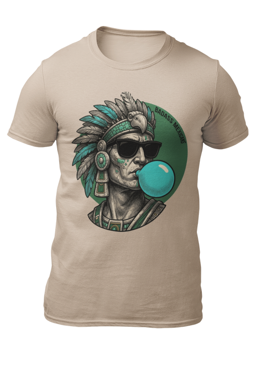 A sand crew-neck t-shirt featuring a circular graphic illustration on the chest. The design depicts an Aztec ruler or warrior chief in profile, wearing a highly detailed traditional feathered headdress and ear spools in shades of turquoise, green, and gray. The character is styled with a modern twist, wearing black sunglasses and blowing a large, bright light-blue bubblegum bubble. The entire illustration is set against a dark green solid circular background with the words "BADASS MEXICANS" written