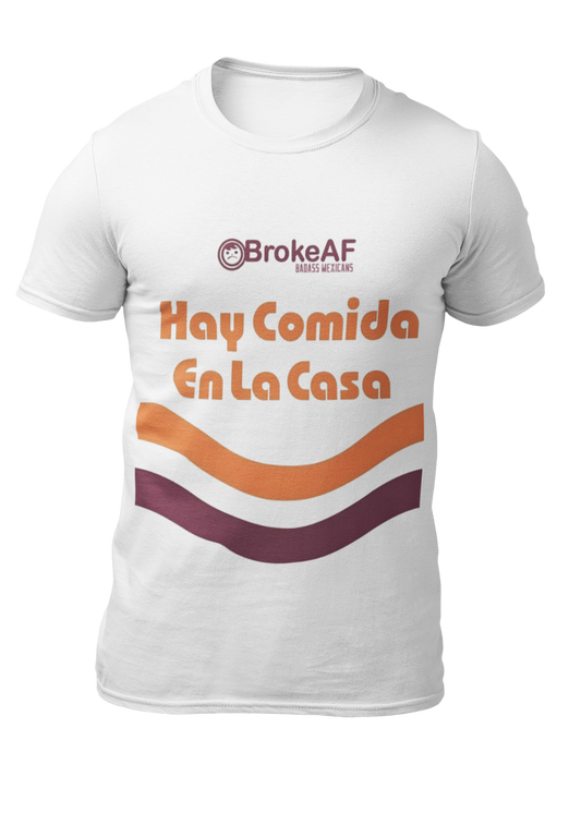 White t-shirt featuring the phrase “Hay Comida En La Casa” in a retro instant noodle-inspired design with orange and brown accents.