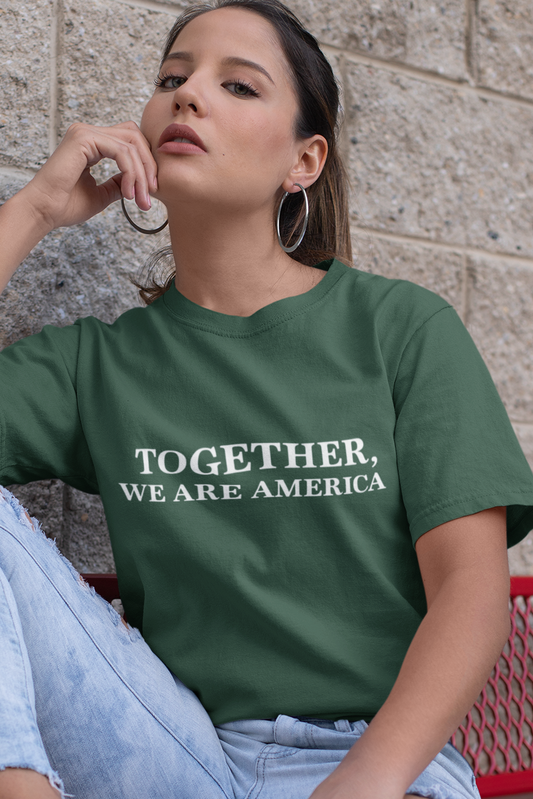 Woman wearing a green unisex shirt, featuring the phrase “Together, We Are America” printed in bold white letters across the chest.