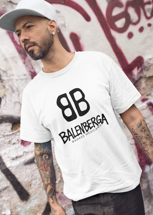tattooed-man-walking-while-wearing-a-t-shirt- showing a close-up, front view of a premium white graphic t-shirt. On the center of the chest, a large black logo features two "B" characters mirrored and interlocked back-to-back. Directly below the logo, the word "BALENBERGA" is printed in an edgy, stylized white paint-stroke font, with "BADASS MEXICANS" cleanly written underneath in a small, minimalist font.