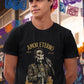 Black t-shirt featuring a detailed Catrín graphic of Juan Gabriel holding a microphone surrounded by golden text reading "AMOR ETERNO E INOLVIDABLE".