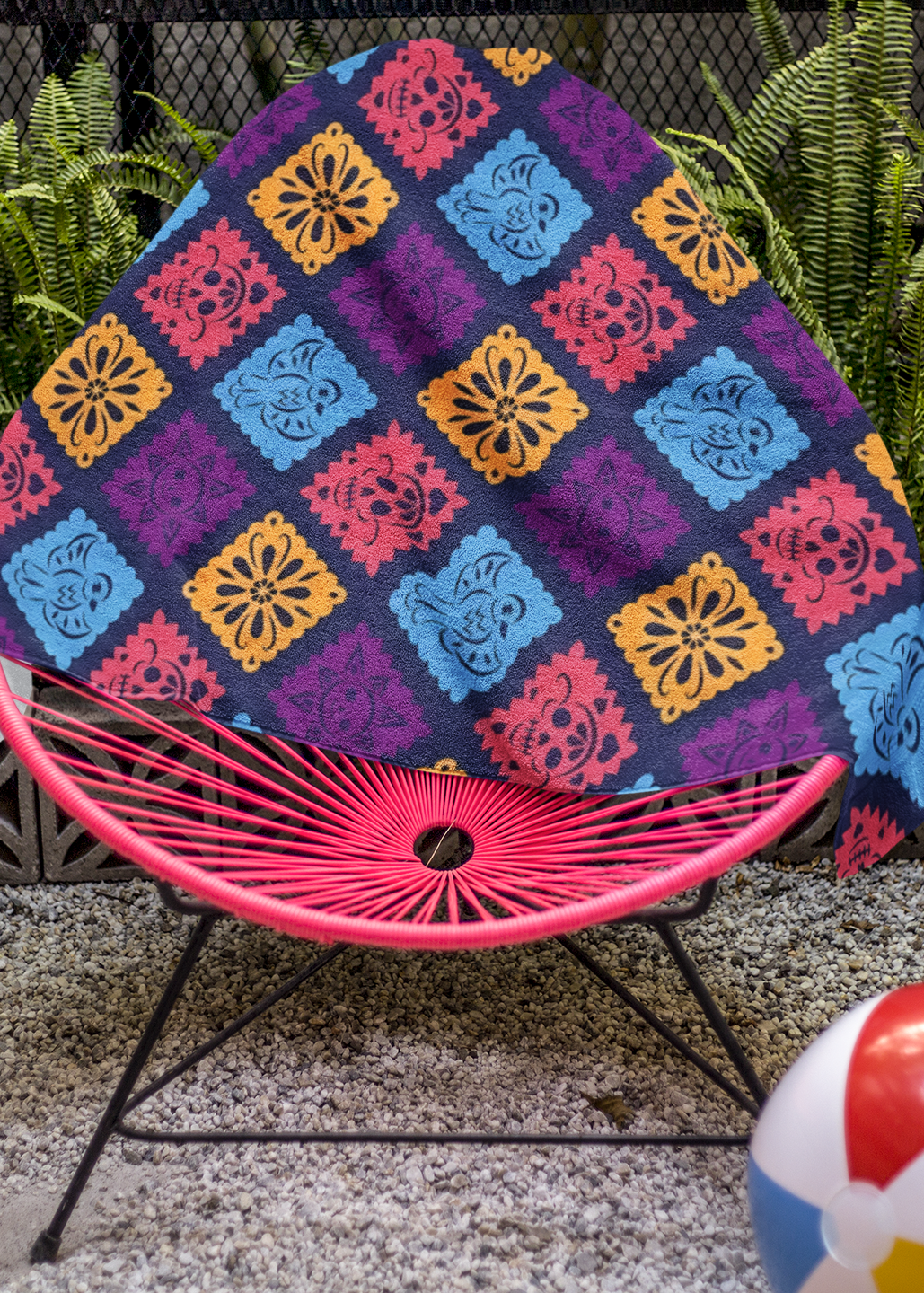 purple papel picado inspired beach towel with colorful skulls suns birds and floral shapes in mexican folk art style