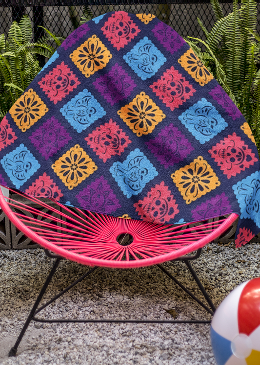 purple papel picado inspired beach towel with colorful skulls suns birds and floral shapes in mexican folk art style
