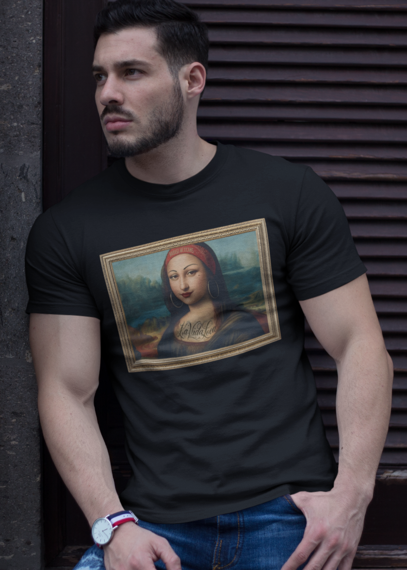 A man wearing a Black unisex t-shirt, featuring a parody artwork inspired by the Mona Lisa portrayed with a chola aesthetic, including hoop earrings, a headband, and visible tattoos, framed like a classical painting.