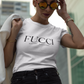 A white lifestyle t-shirt featuring the word "FUCCI" printed in a large, elegant black serif font across the chest. Below it, the brand name "BADASS MEXICANS" is printed in a smaller, clean sans-serif font.