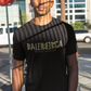 A black streetwear t-shirt showcasing the word "BALENBERGA" across the chest in a heavy, textured, geometric block font with alternating mirrored letters in an olive-beige tone. Underneath, "BADASS MEXICANS" is printed in a clean, sharp matching font.