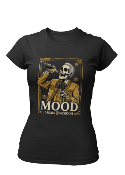A high-quality graphic on a black t-shirt featuring a skeleton dressed in a traditional gold and brown Mariachi suit. The skeleton is holding a vintage microphone and drinking from a bottle. The design is framed in an elegant vintage border with the word "MOOD" in large serif letters and "BADASS MEXICANS" underneath.