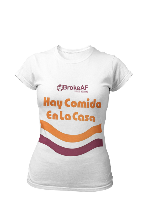 White t-shirt featuring the phrase “Hay Comida En La Casa” in a retro instant noodle-inspired design with orange and brown accents.