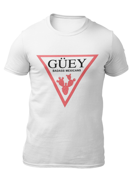 A white crew-neck t-shirt featuring a large, inverted pinkish-red triangle graphic printed on the chest. Inside the upper section of the triangle, the word "GÜEY" is written in a bold, black serif font, with the words "BADASS MEXICANS" printed right underneath in a smaller black sans-serif font. Centered at the bottom point of the triangle is a detailed graphic illustration of a prickly pear cactus (nopal) in a matching pinkish-red color.