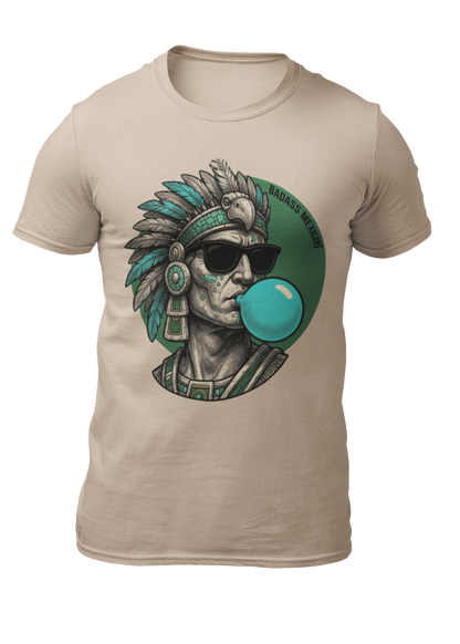A sand crew-neck t-shirt featuring a circular graphic illustration on the chest. The design depicts an Aztec ruler or warrior chief in profile, wearing a highly detailed traditional feathered headdress and ear spools in shades of turquoise, green, and gray. The character is styled with a modern twist, wearing black sunglasses and blowing a large, bright light-blue bubblegum bubble. The entire illustration is set against a dark green solid circular background with the words "BADASS MEXICANS" written