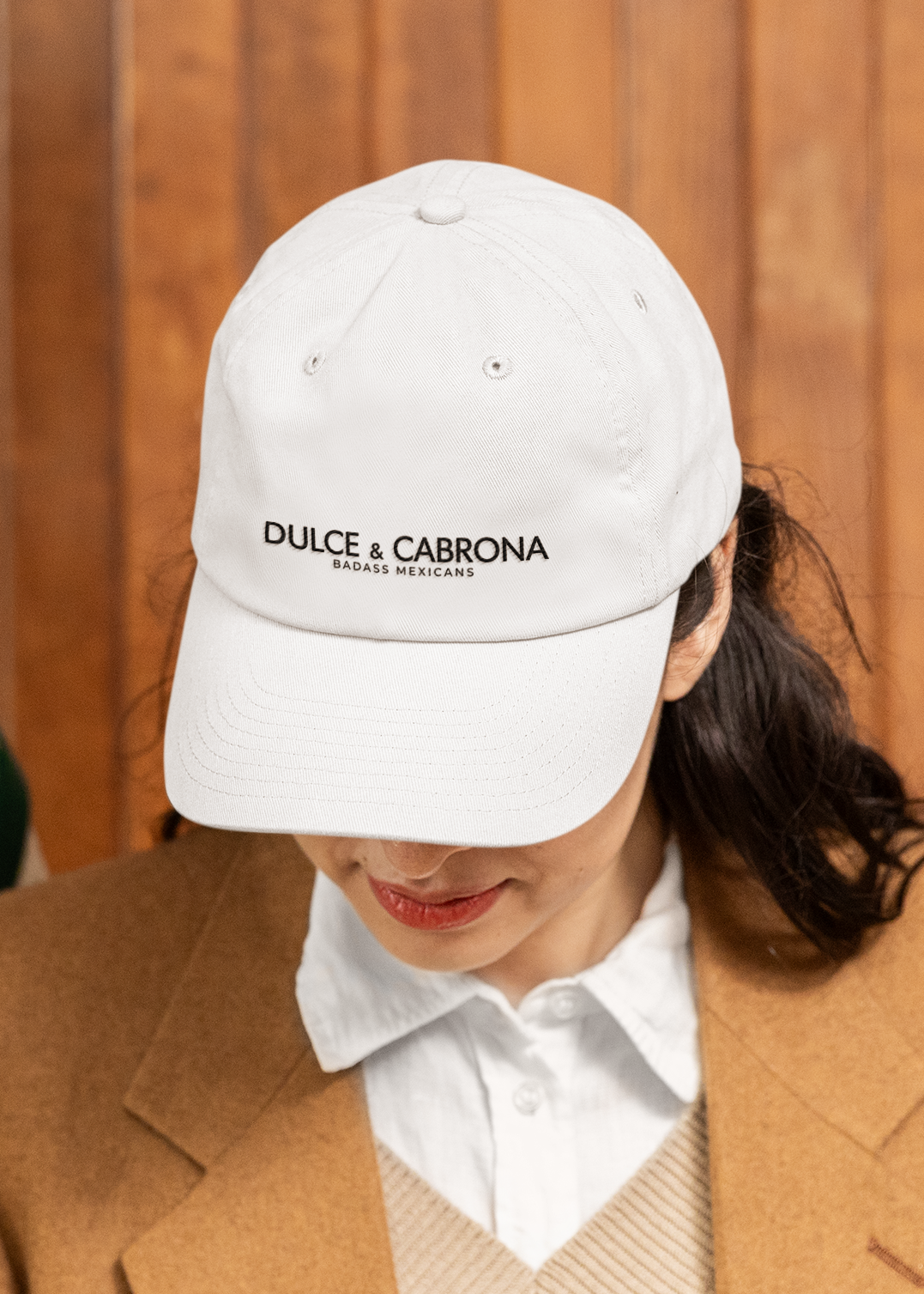 white dad hat On the front panel of the hat, the words "DULCE & CABRONA" are printed in a clean black luxury-style serif font, with "BADASS MEXICANS" printed right underneath in a smaller size.
