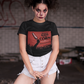 Black crew-neck t-shirt featuring a red retro movie poster graphic with a hand holding a spiced corn on a stick above a cornfield silhouette.