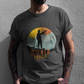 Black crew-neck t-shirt with a colorful retro circular sunset graphic showing a mountain hiker silhouette pointing forward above orange and yellow text "Vete a la verga".