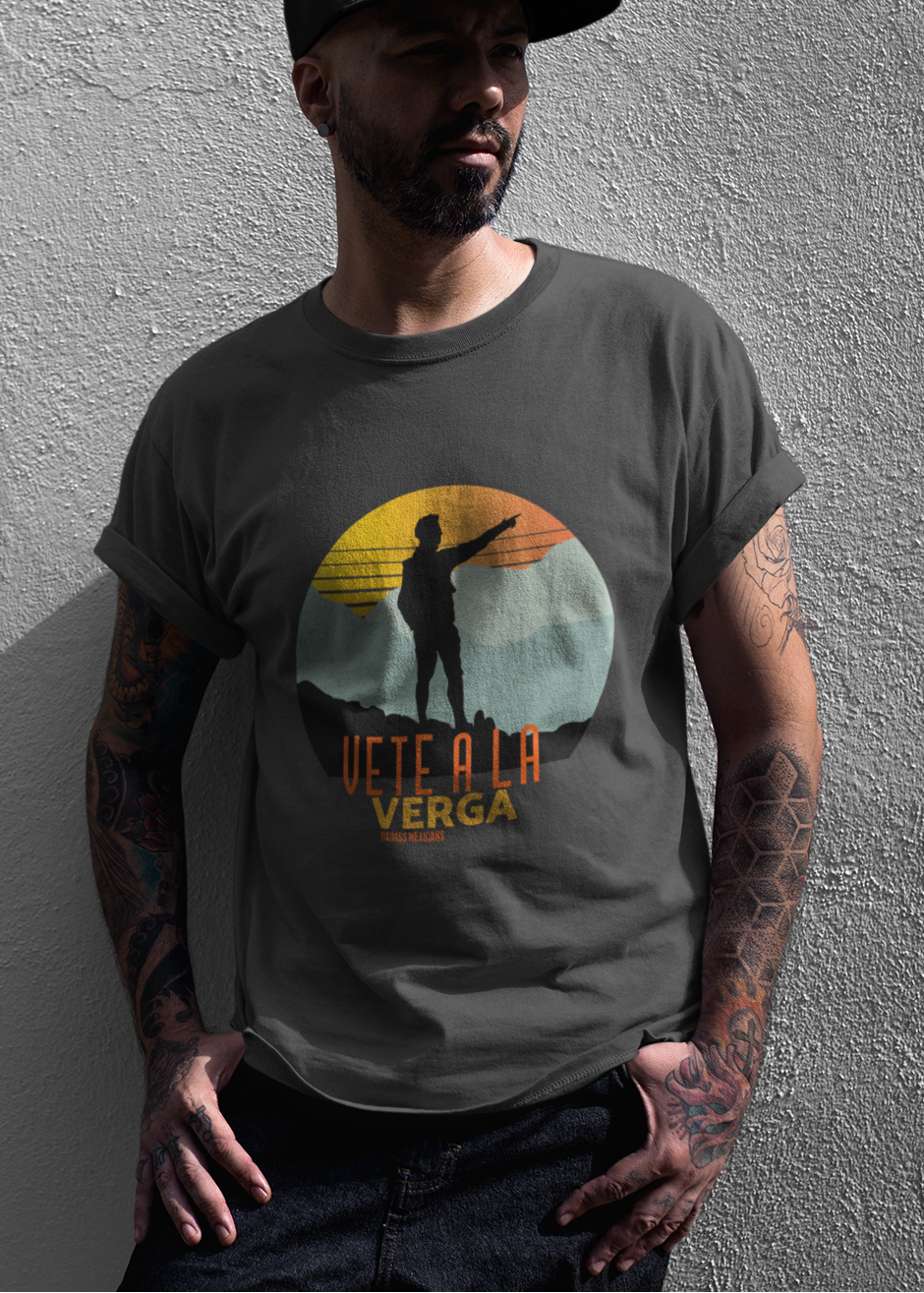 Black crew-neck t-shirt with a colorful retro circular sunset graphic showing a mountain hiker silhouette pointing forward above orange and yellow text "Vete a la verga".