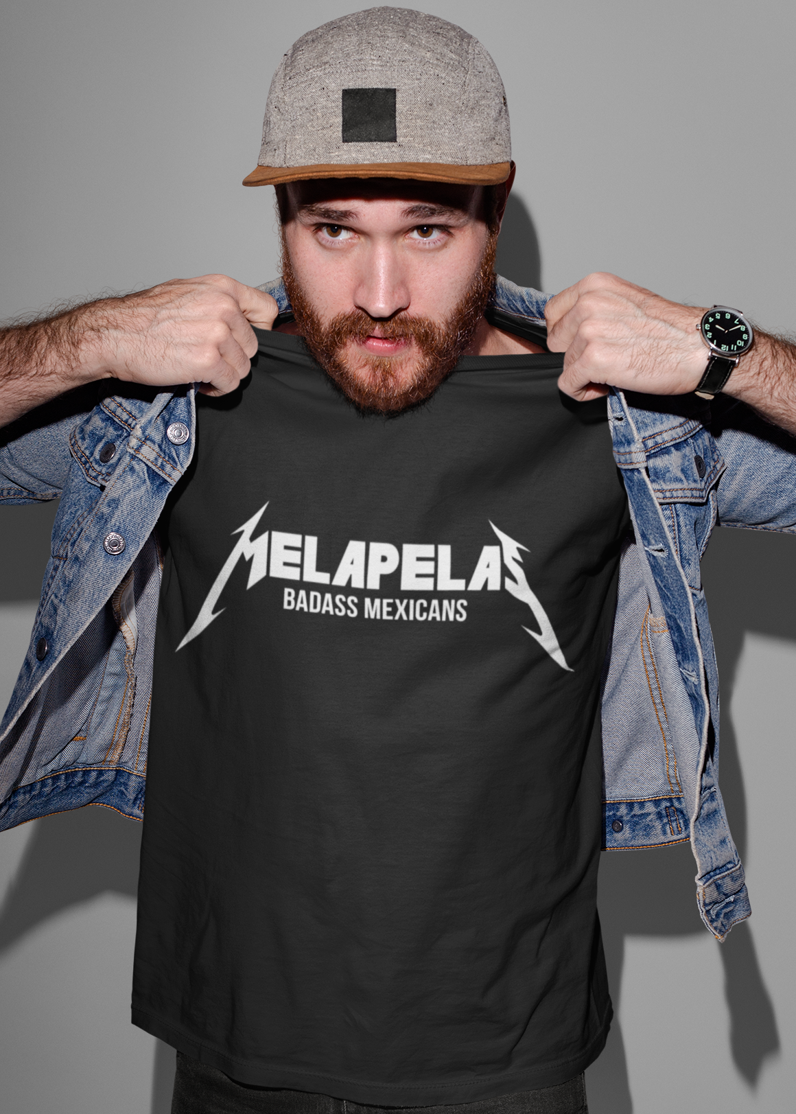 Black crew-neck t-shirt with "MELAPELAS" printed across the chest in a sharp white heavy-metal lightning font, with "BADASS MEXICANS" in small white text below.
