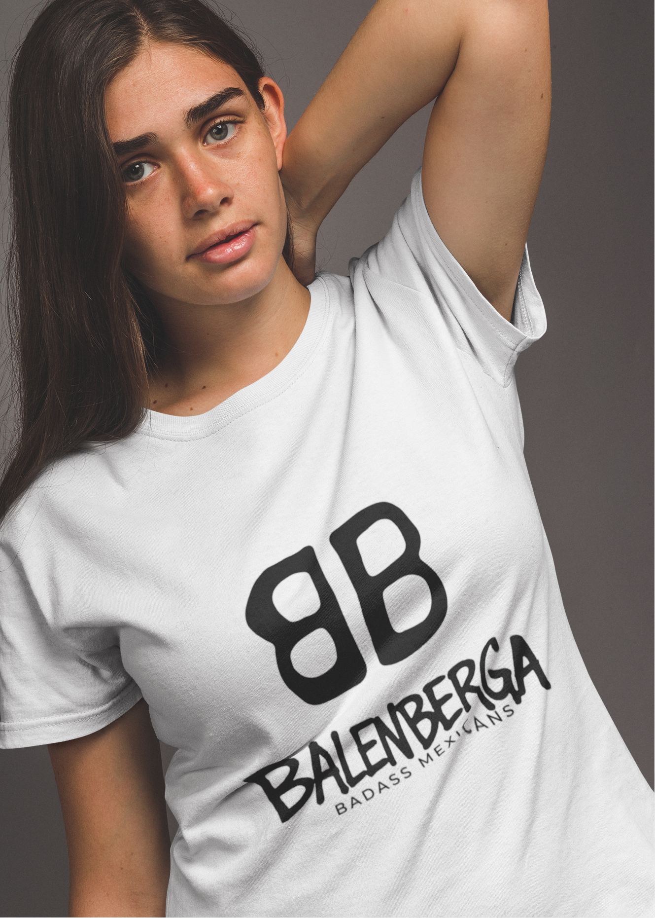 front view of a premium white graphic t-shirt. On the center of the chest, a large black logo features two "B" characters mirrored and interlocked back-to-back. Directly below the logo, the word "BALENBERGA" is printed in an edgy, stylized white paint-stroke font, with "BADASS MEXICANS" cleanly written underneath in a small, minimalist font.