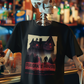 Black t-shirt with a red and beige retro horror movie poster graphic of a haunted house titled "SUEGRA'S HOUSE".