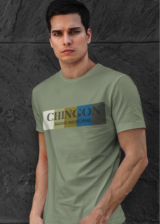 An Military green crew-neck t-shirt featuring a graphic design printed across the chest. The design consists of five vertical color blocks lined up side-by-side in white, beige, gold, blue, and dark gray. Overlaid on these blocks, the word "CHINGON" is printed in a large, elegant dark gray serif font, with the words "BADASS MEXICANS" written directly underneath in a smaller, clean sans-serif typeface.