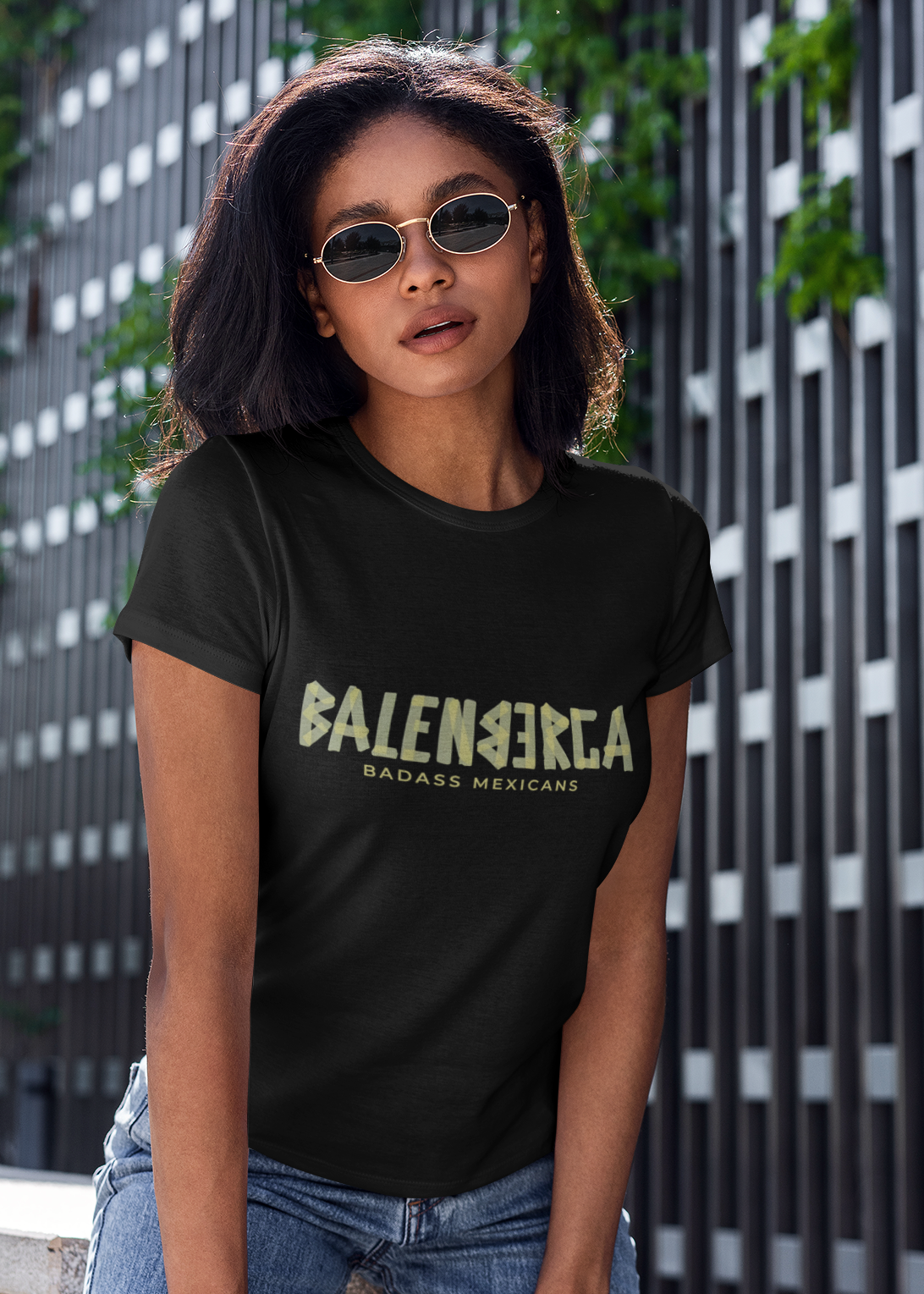 A black streetwear t-shirt showcasing the word "BALENBERGA" across the chest in a heavy, textured, geometric block font with alternating mirrored letters in an olive-beige tone. Underneath, "BADASS MEXICANS" is printed in a clean, sharp matching font.