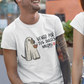 White t-shirt featuring an illustration of a dog dressed as a sheet ghost holding a pumpkin bucket next to text reading "VENGO POR TUS DULCES NALGAS".