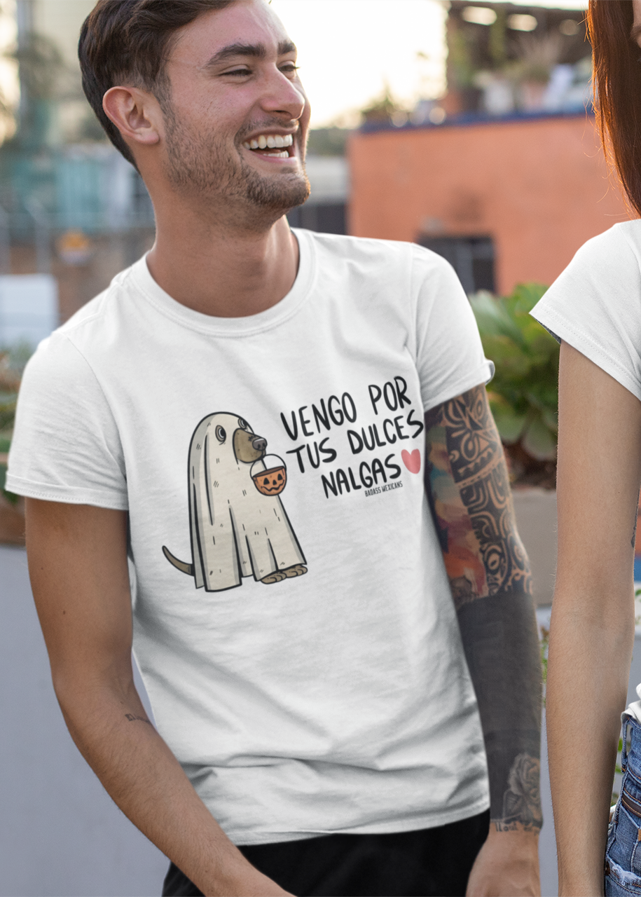 White t-shirt featuring an illustration of a dog dressed as a sheet ghost holding a pumpkin bucket next to text reading "VENGO POR TUS DULCES NALGAS".