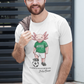 A white crew-neck t-shirt  featuring a colorful graphic illustration of a cute pink axolotl character dressed in a green Mexico soccer jersey, white shorts, and soccer cleats. The axolotl is standing with one foot on a classic black and white soccer ball. Below the design, it reads "El Axolotl by BADASS MEXICANS" with a cursive signature.