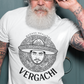 A white t-shirt featuring a large black graphic. The design includes a circular Aztec calendar-style background with a stylized man wearing a traditional Mexican charro hat in the center. The word "VERGACHI" is printed in a bold, arched serif font underneath the graphic, with "BADASS MEXICANS" in a small arch above it.