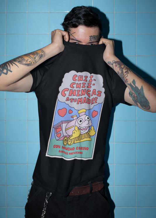 A person wearing a black unisex t-shirt featuring a colorful Valentine-style illustration with Spanish text that reads "Chingas a tu Madre" “Con Cariño,” designed as a humorous and playful Mexican-inspired message.
