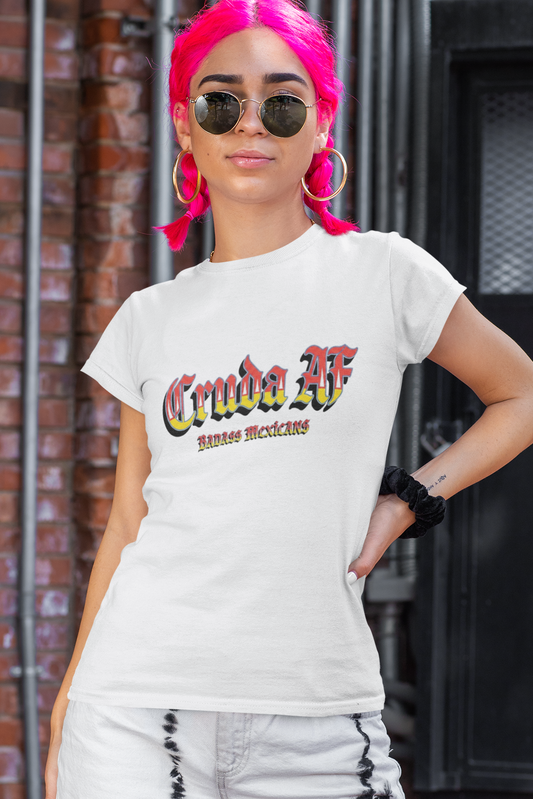 A white fitted women's crew-neck t-shirt featuring the text "Cruda AF" printed across the chest in a bold, stylized Gothic font. The letters feature a horizontal color gradient transition from red at the top, fading into yellow and white at the bottom, outlined in black with a heavy black drop shadow. Directly below, the words "BADASS MEXICANS" are printed in a smaller, matching Gothic font with the same red, yellow, and white gradient and drop shadow effect.