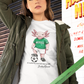 A white crew-neck t-shirt  featuring a colorful graphic illustration of a cute pink axolotl character dressed in a green Mexico soccer jersey, white shorts, and soccer cleats. The axolotl is standing with one foot on a classic black and white soccer ball. Below the design, it reads "El Axolotl by BADASS MEXICANS" with a cursive signature.