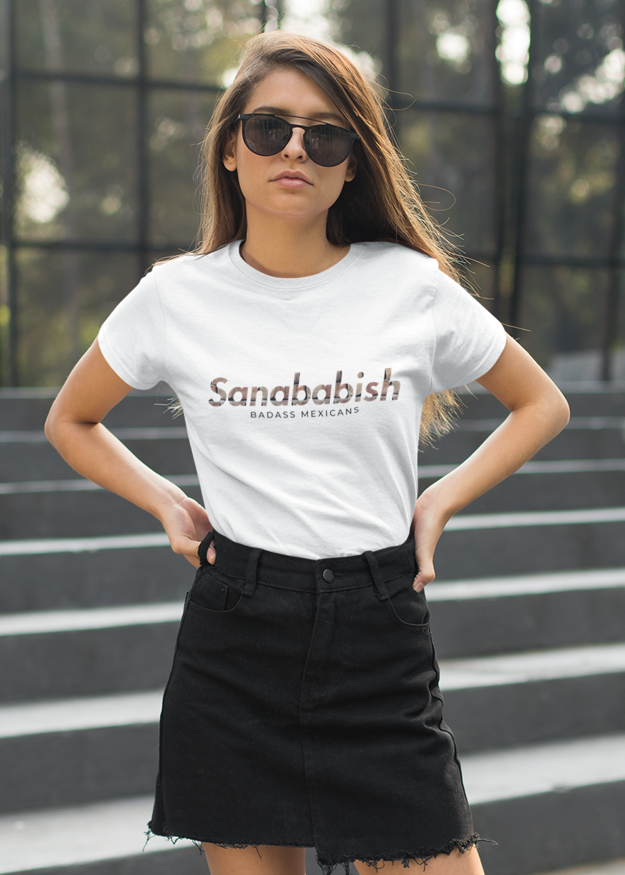 White crew-neck t-shirt with "Sanababish" printed across the chest in a stylized font with a bricks textured pattern, and "BADASS MEXICANS" in small black text below.