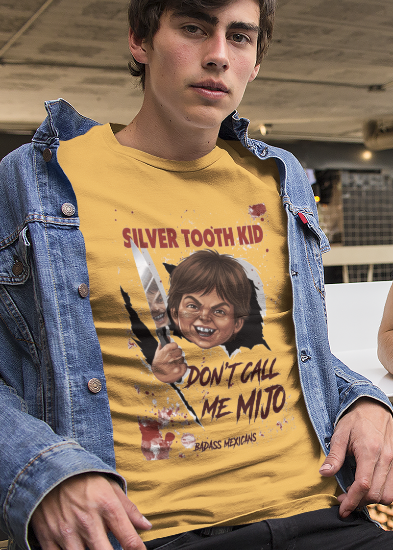 Yellow graphic t-shirt featuring a creepy killer doll parody tearing through a wall with text reading "SILVER TOOTH KID DON'T CALL ME MIJO".
