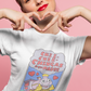 Woman wearing white t-shirt featuring a colorful Valentine-style illustration with Spanish text that reads "Chingas a tu Madre" “Con Cariño,” designed as a humorous and playful Mexican-inspired message.
